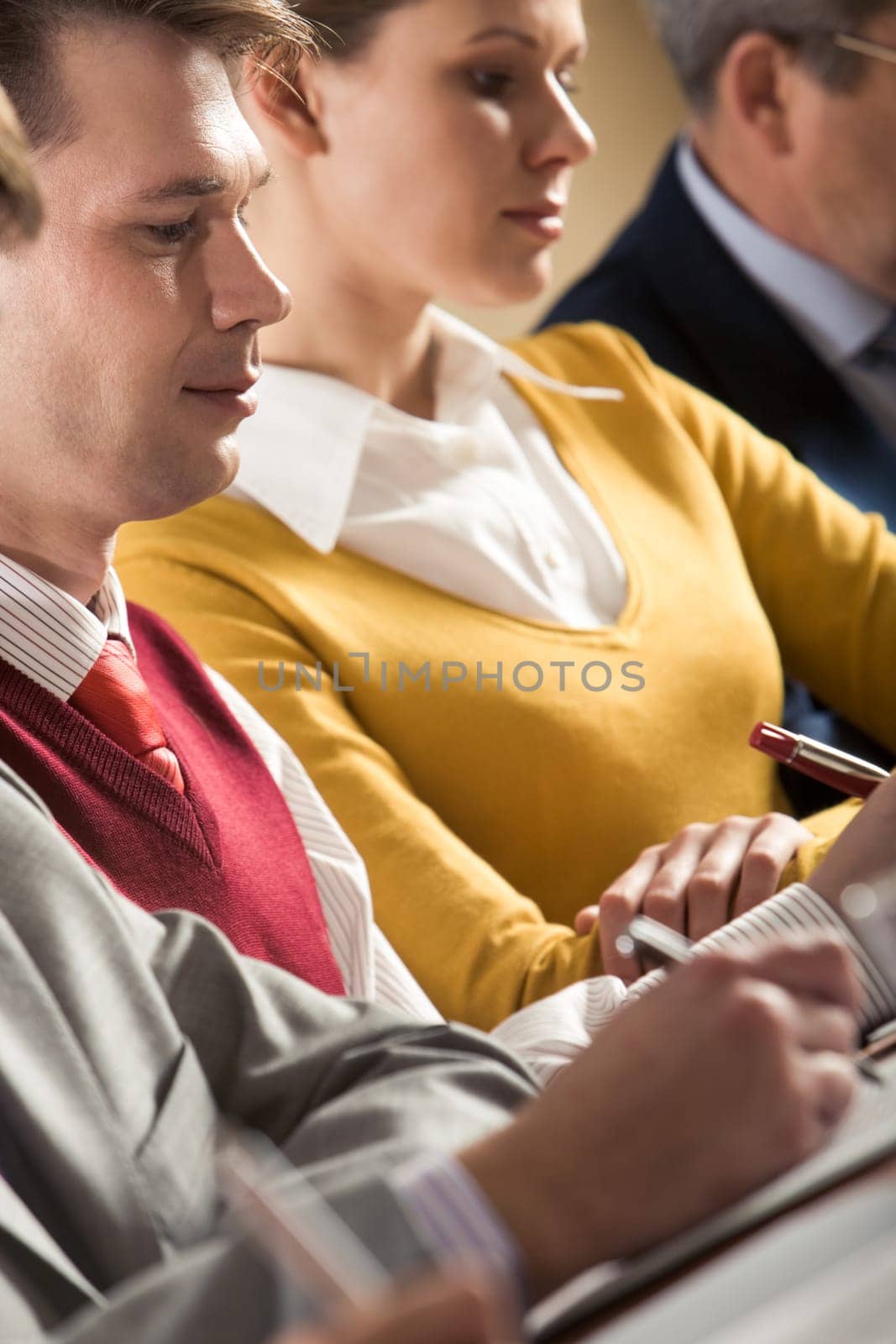 Confident businessman writing summary of his work with woman at background