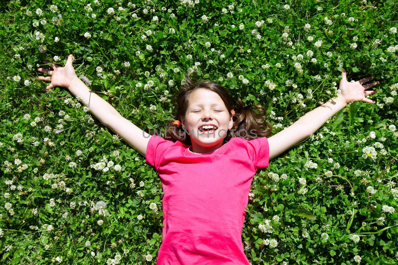 Portrait of a joyful little girl lying on grass