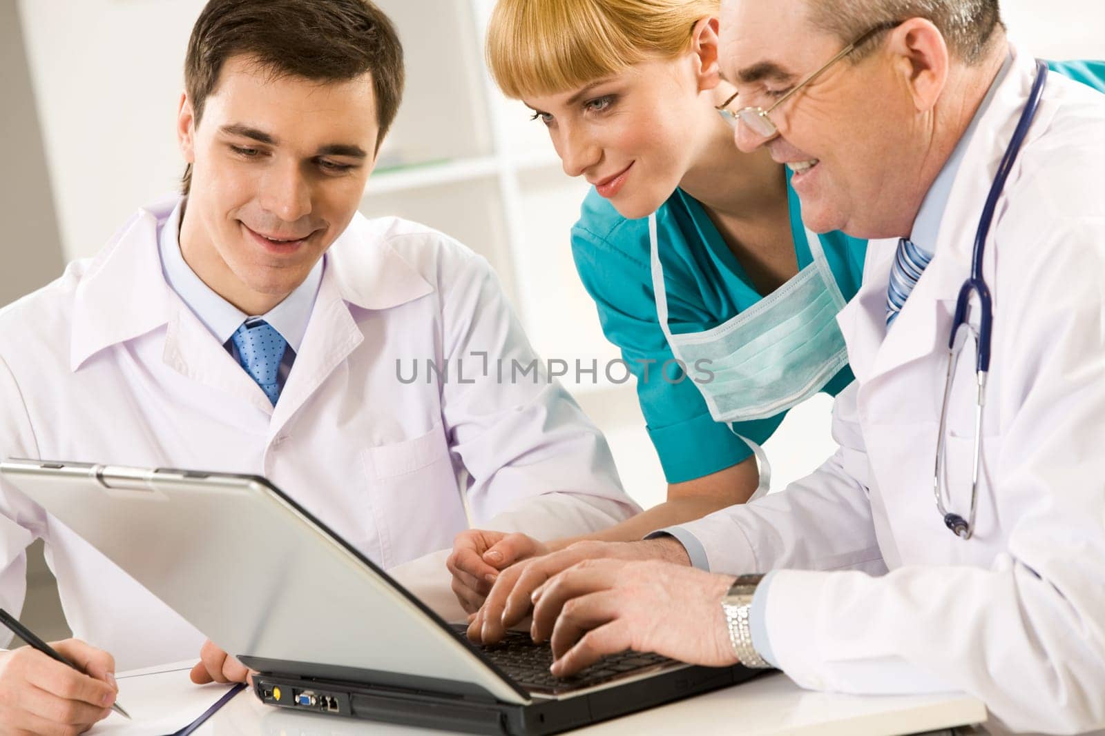 Three therapists looking at laptop screen while elderly man pressing keypad buttons