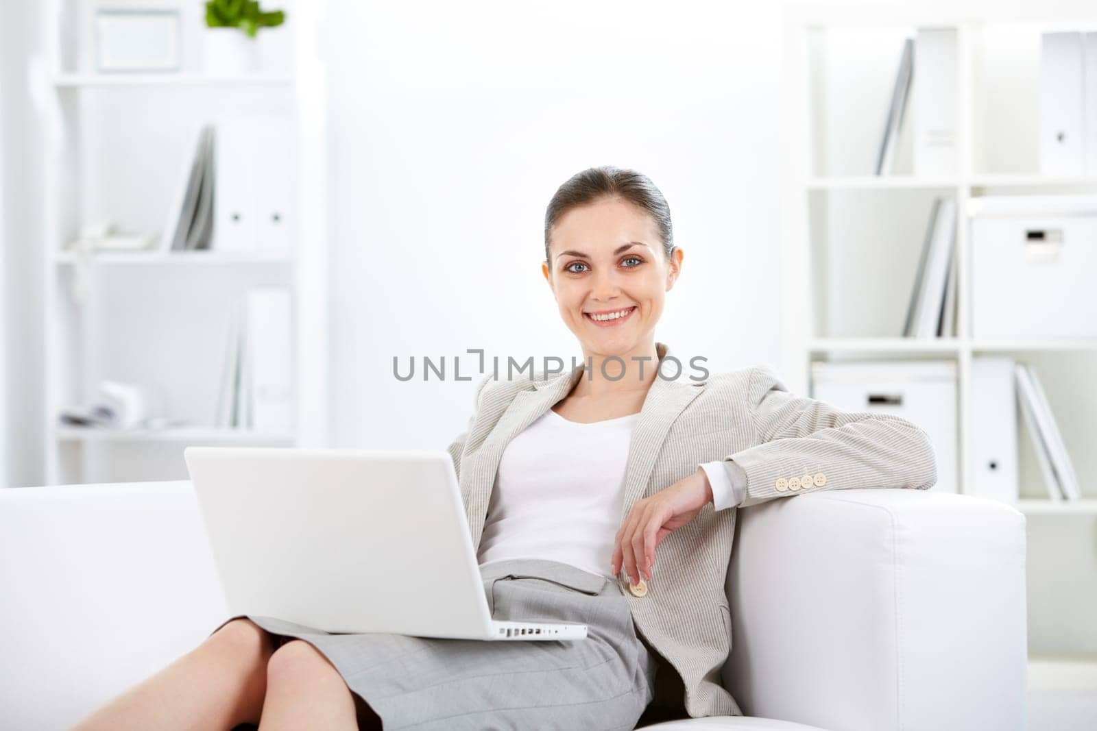 Portrait of smiling businesswoman with laptop looking at camera in office