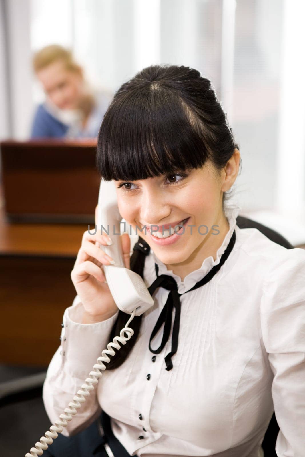 Pretty secretary speaking on the phone in the office