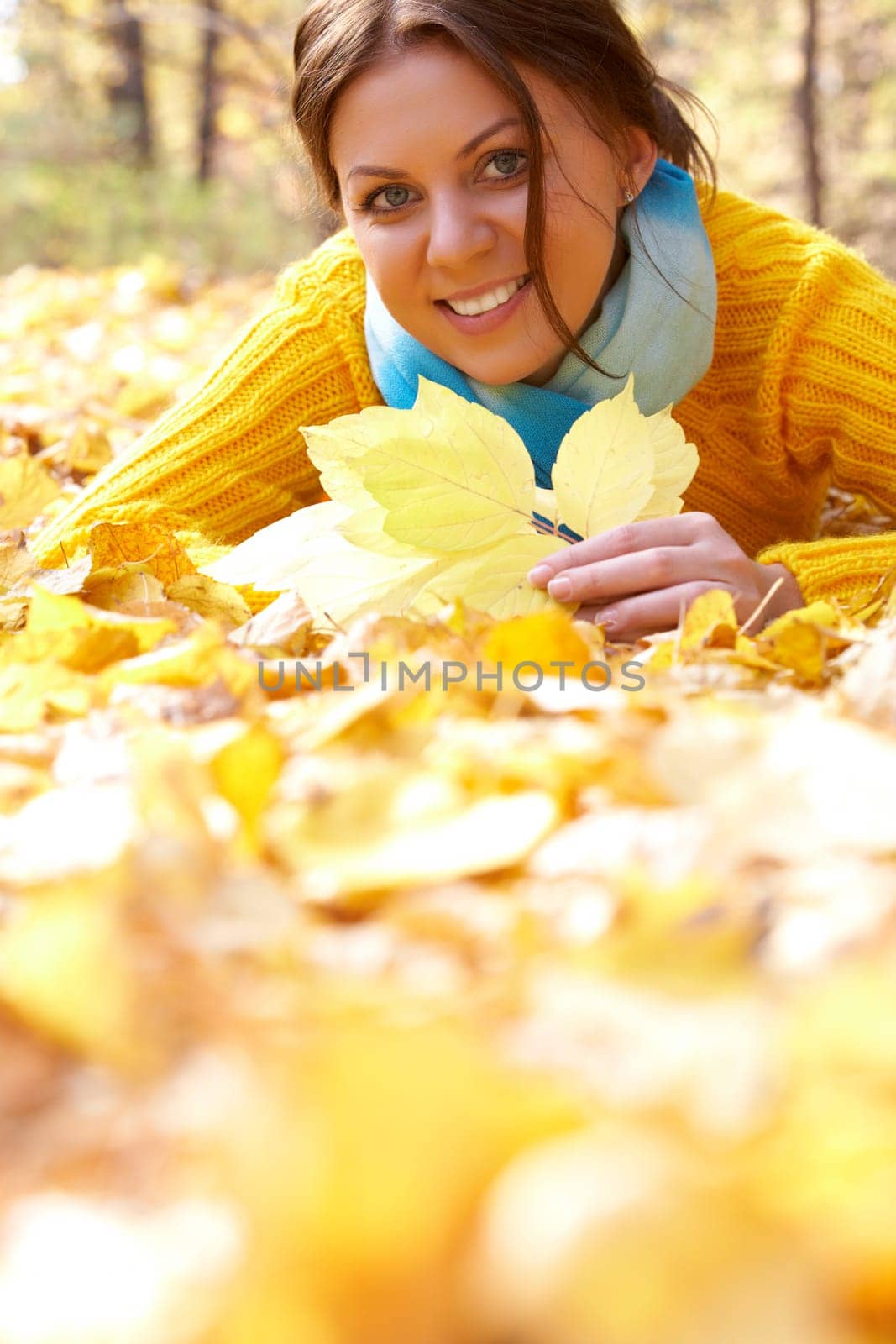 Image of resting young woman lying on foliage in autumn