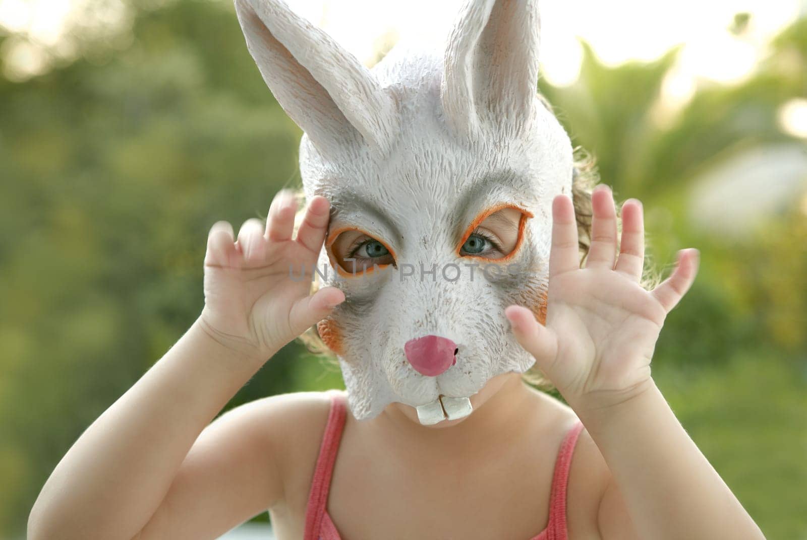 Toddler girl with rabbit white mask scaring to camera