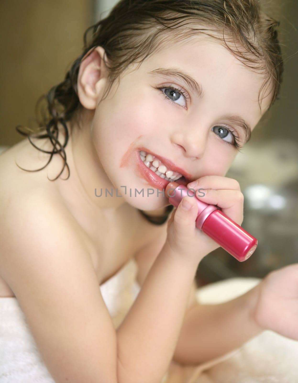 Little girl playing with lipstick makeup on the bathroom