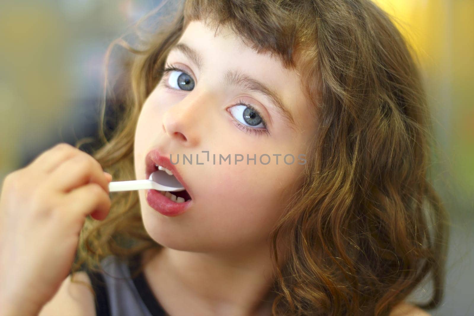brunette little girl eating  plastic spoon