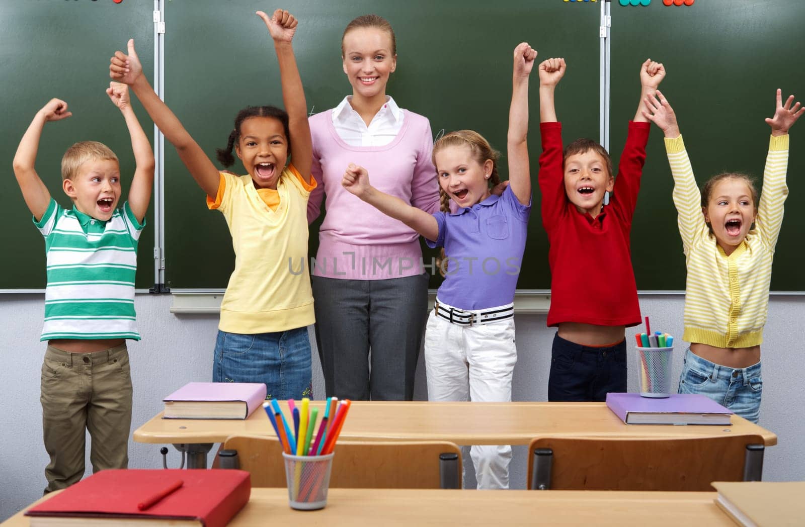 Line of cute schoolchildren raising arms with their teacher in the middle