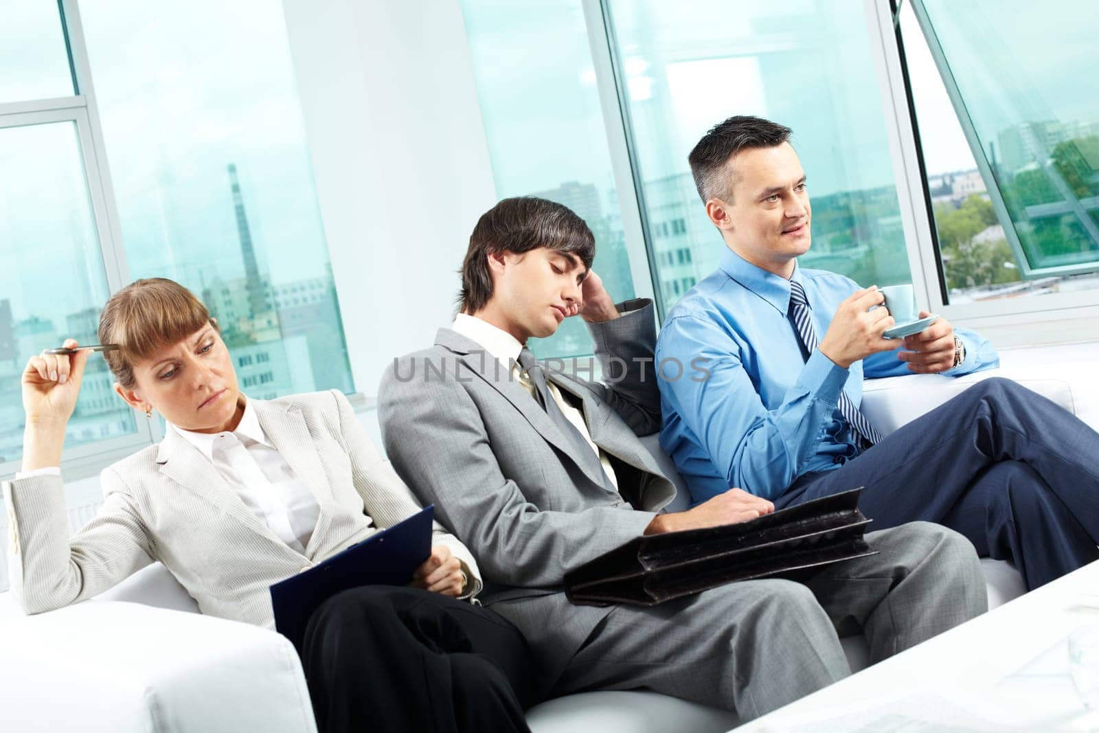 Three office workers sitting on sofa after hard workday