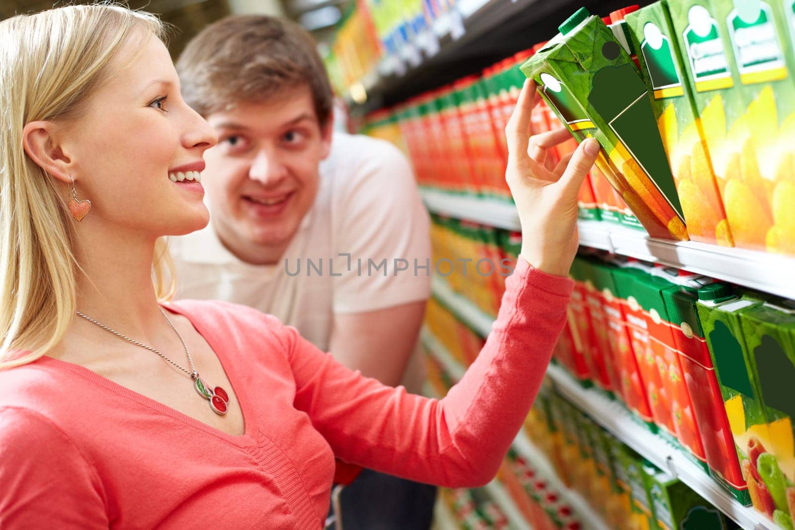 Portrait of happy woman taking pack of juice and man watching her