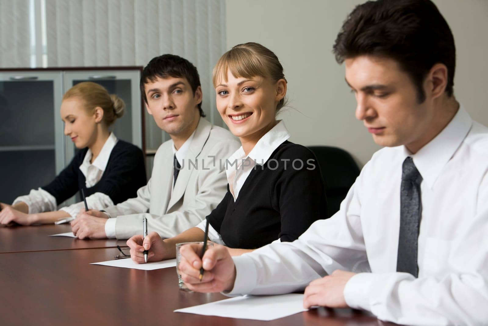 Successful young people are sitting at the table and filling a forms