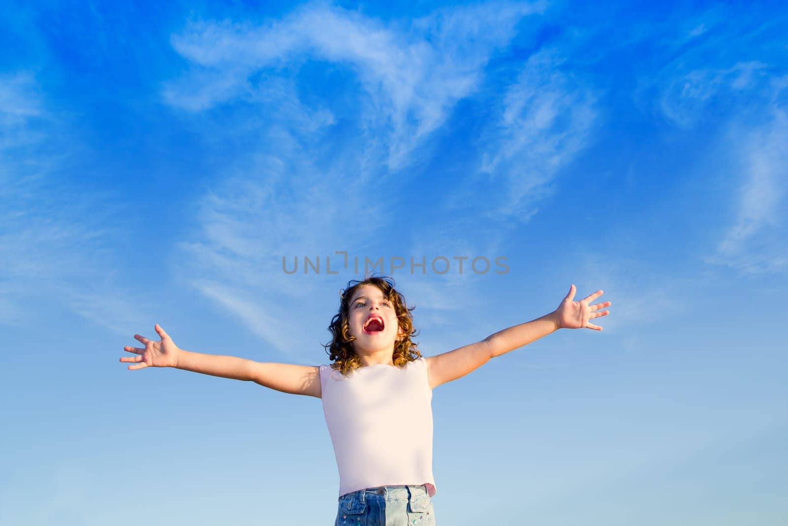 Girl open arms outdoor under blue sky with happiness gesture