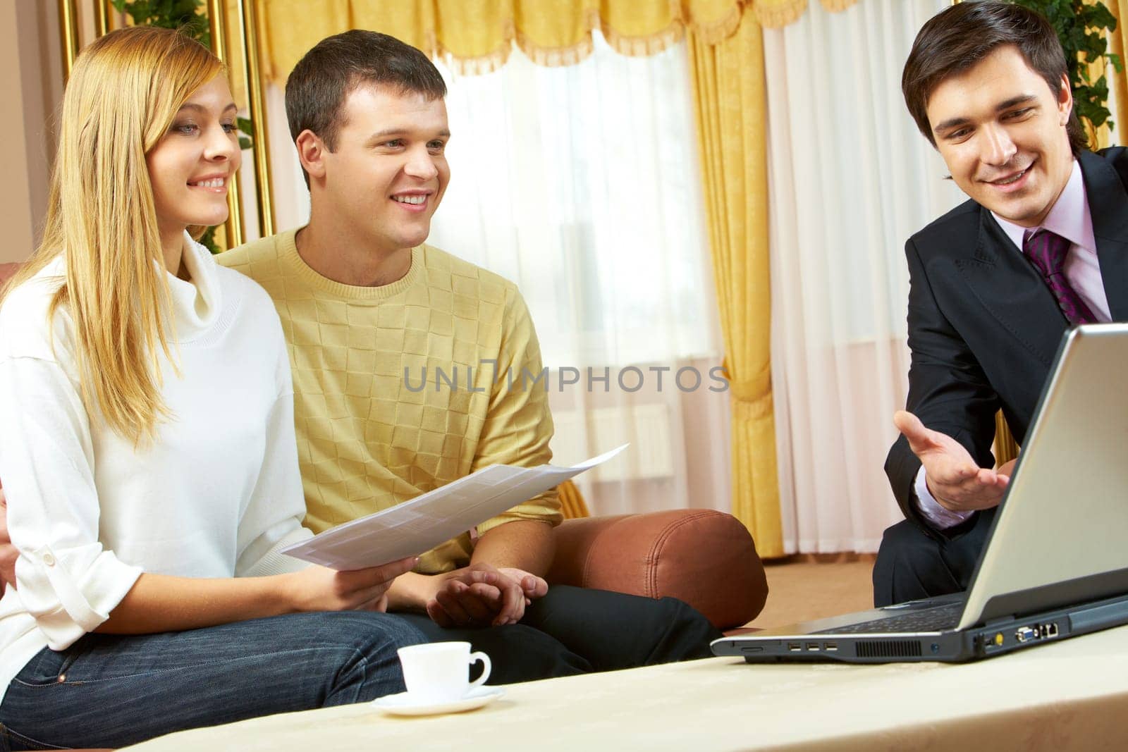 Portrait of a businessman explaining something in laptop to young couple