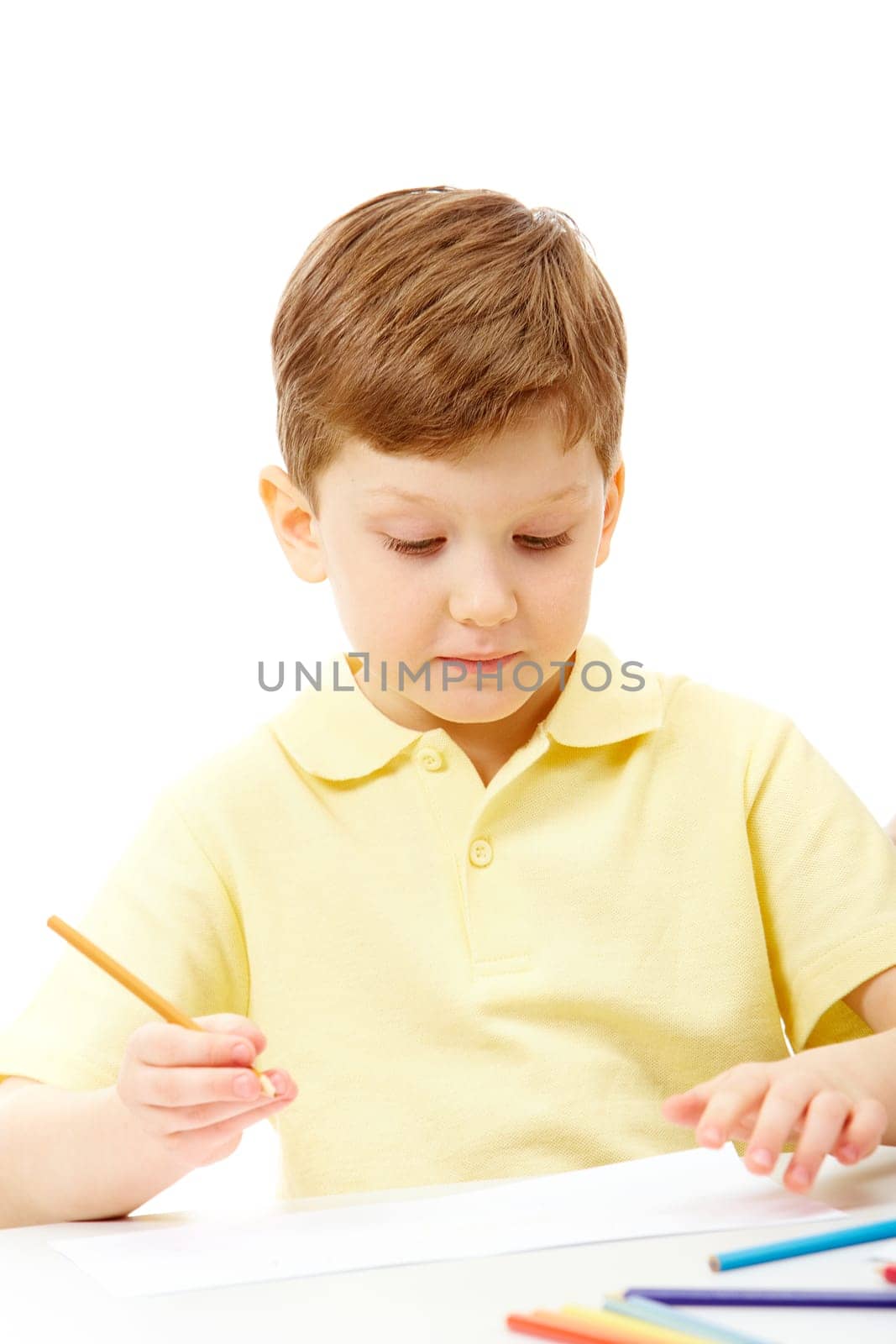 Portrait of young boy holding pencil and looking at the paper
