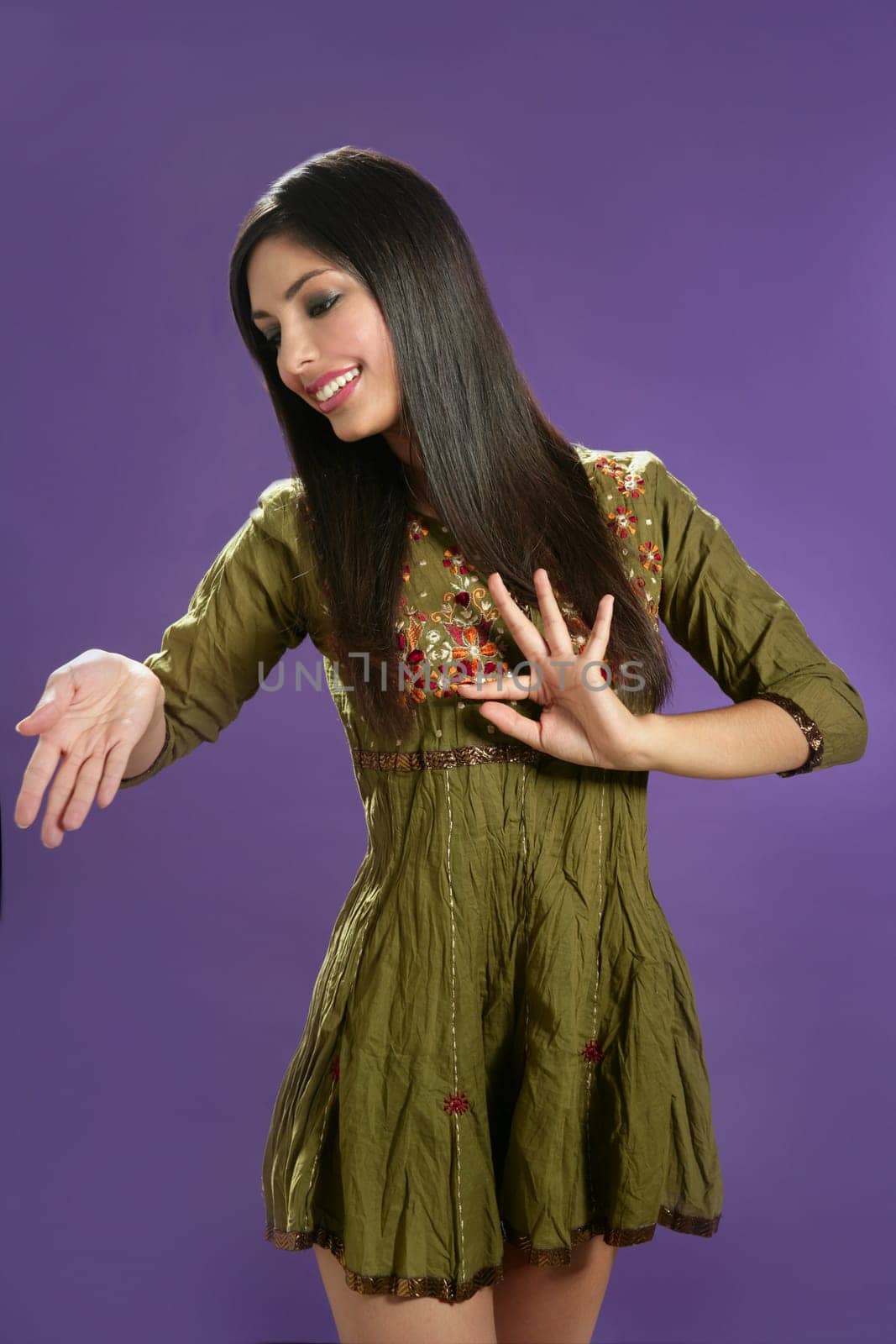 Beautiful indian young brunette woman posing hands on purple background
