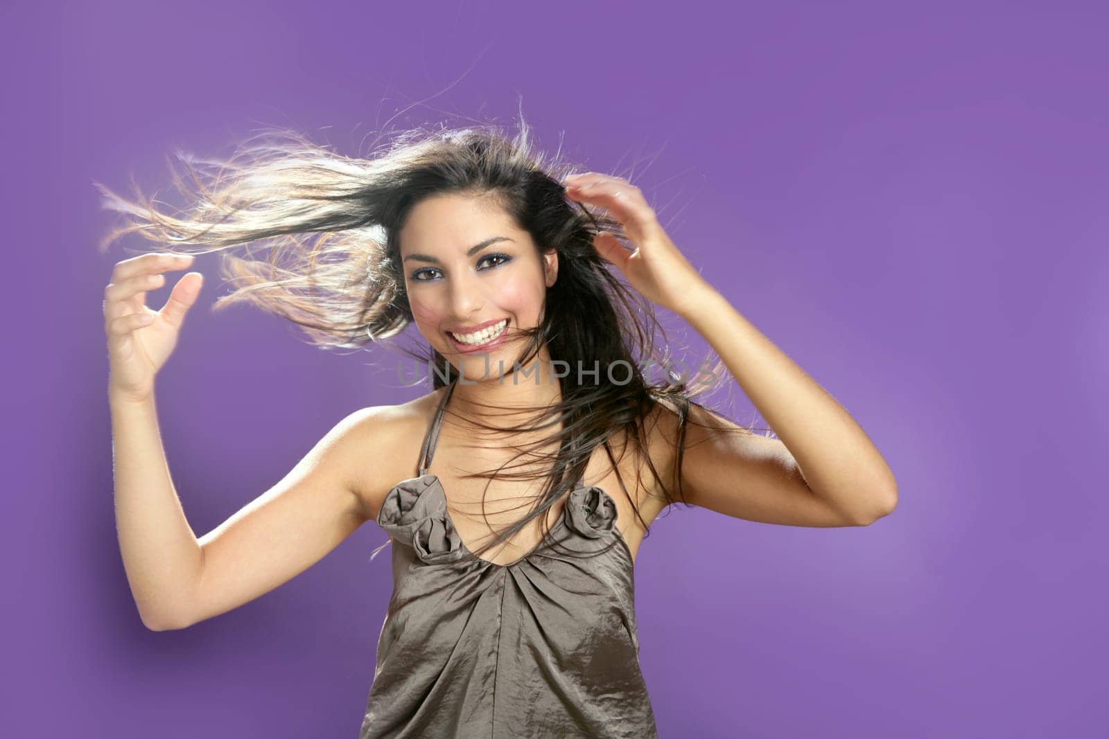 Brunette indian beautiful woman dancing at studio on purple background