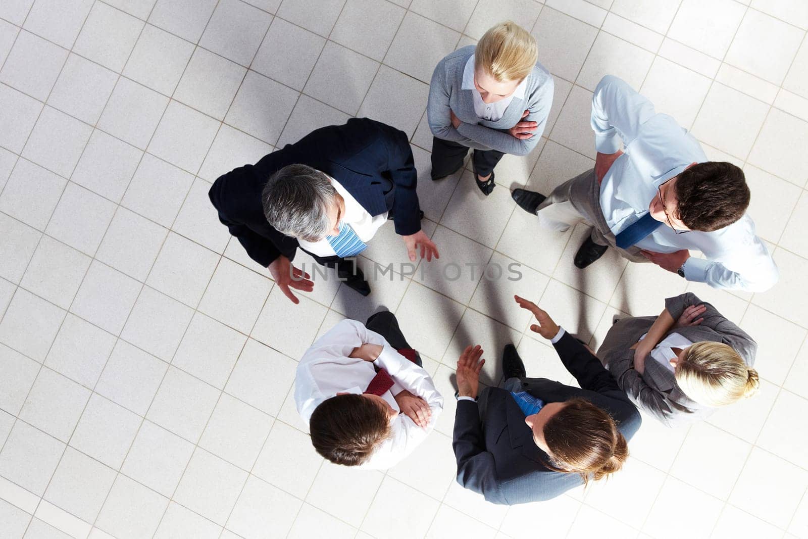Above angle of several smart associates talking to each other at meeting