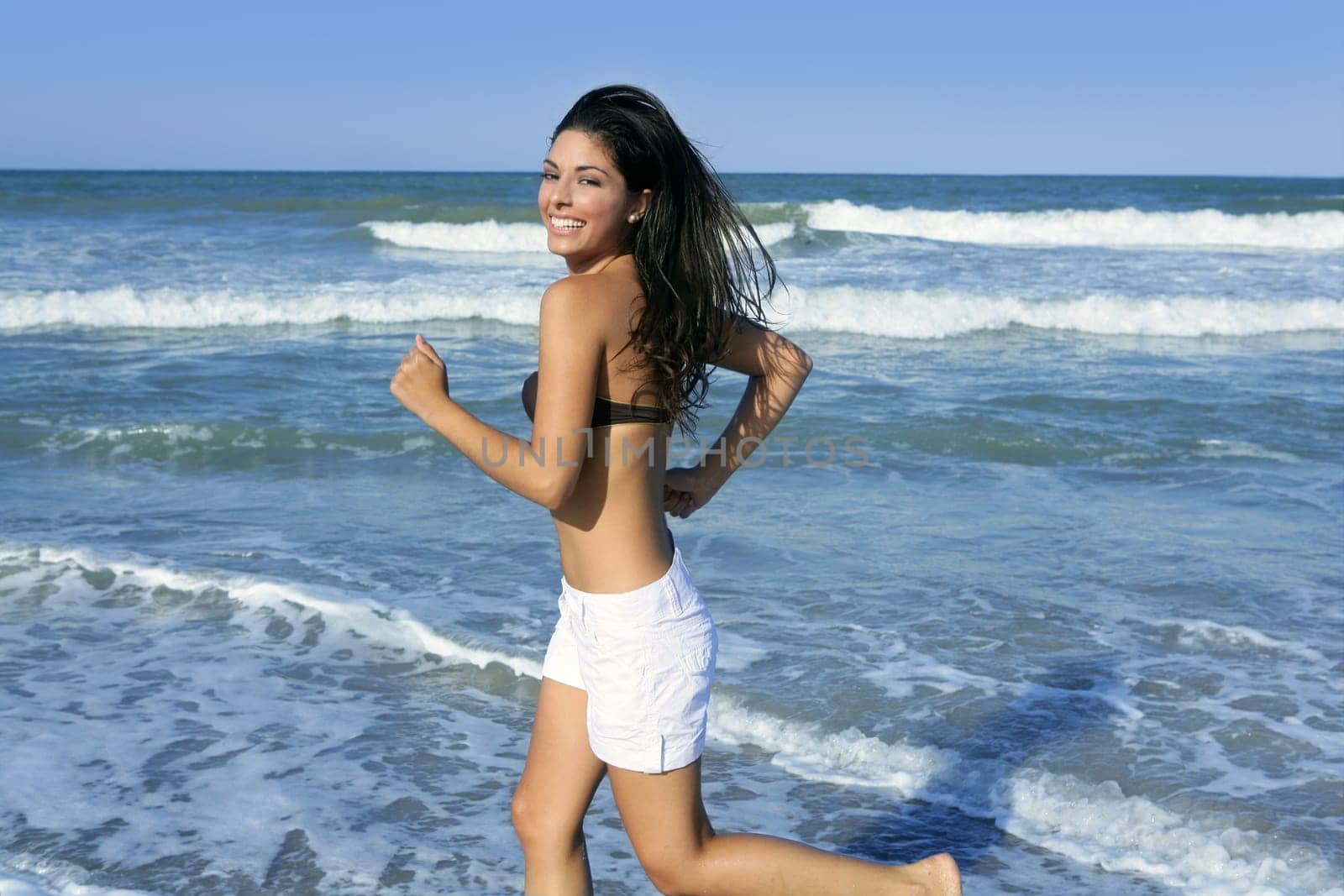 Beautiful summer brunette girl jumping on the blue beach