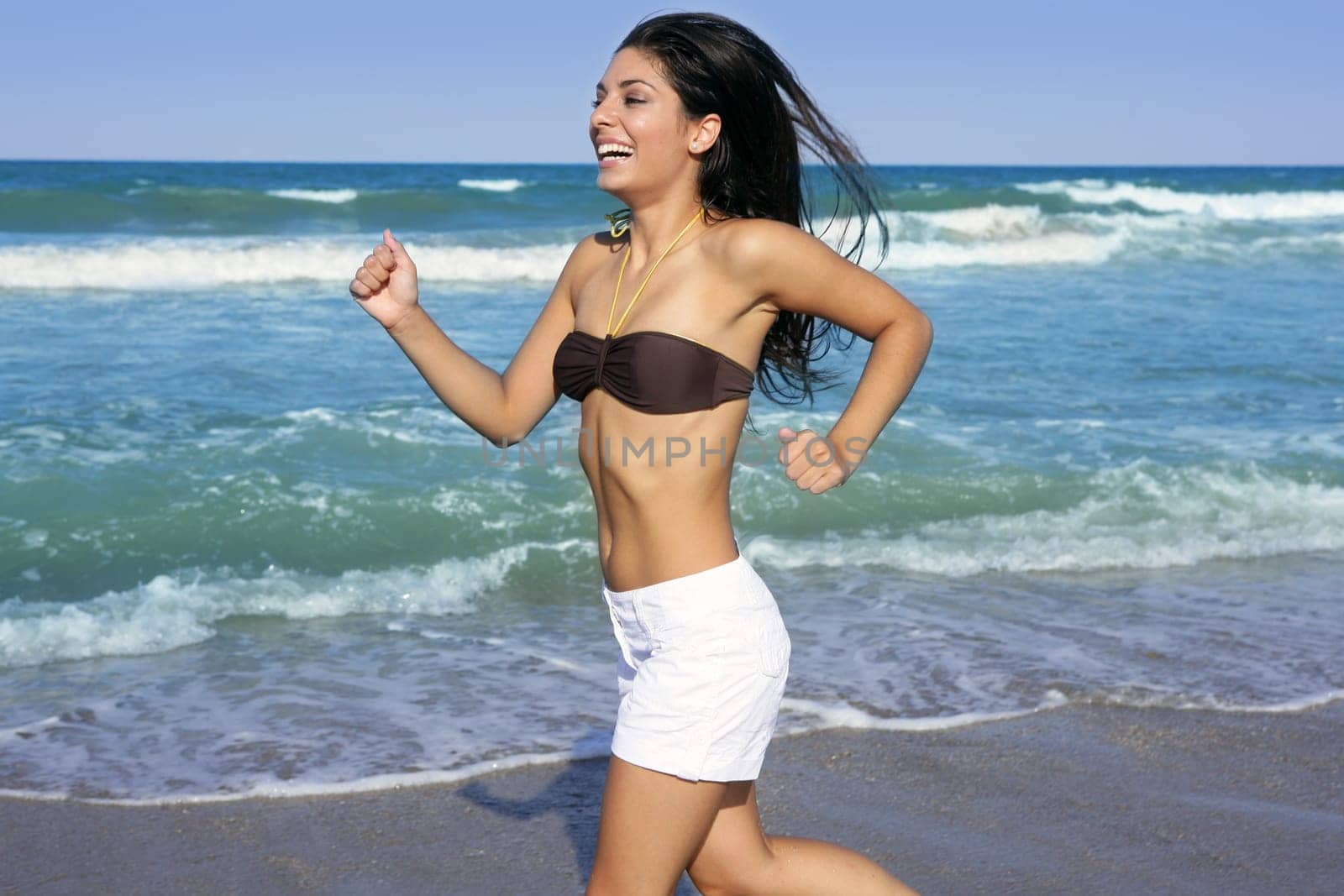 Beautiful summer indian brunette girl jumping on the blue beach