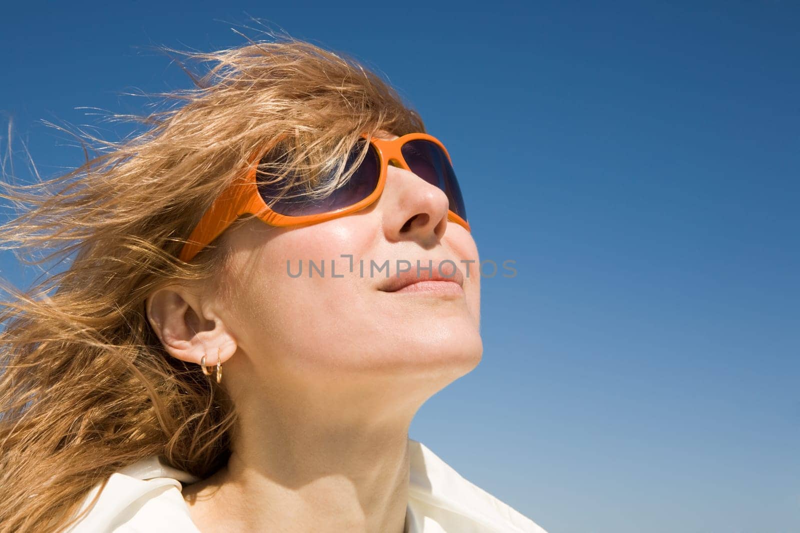 Portrait of pretty blonde in white bikini smiling with her eyes shut on hot summer day