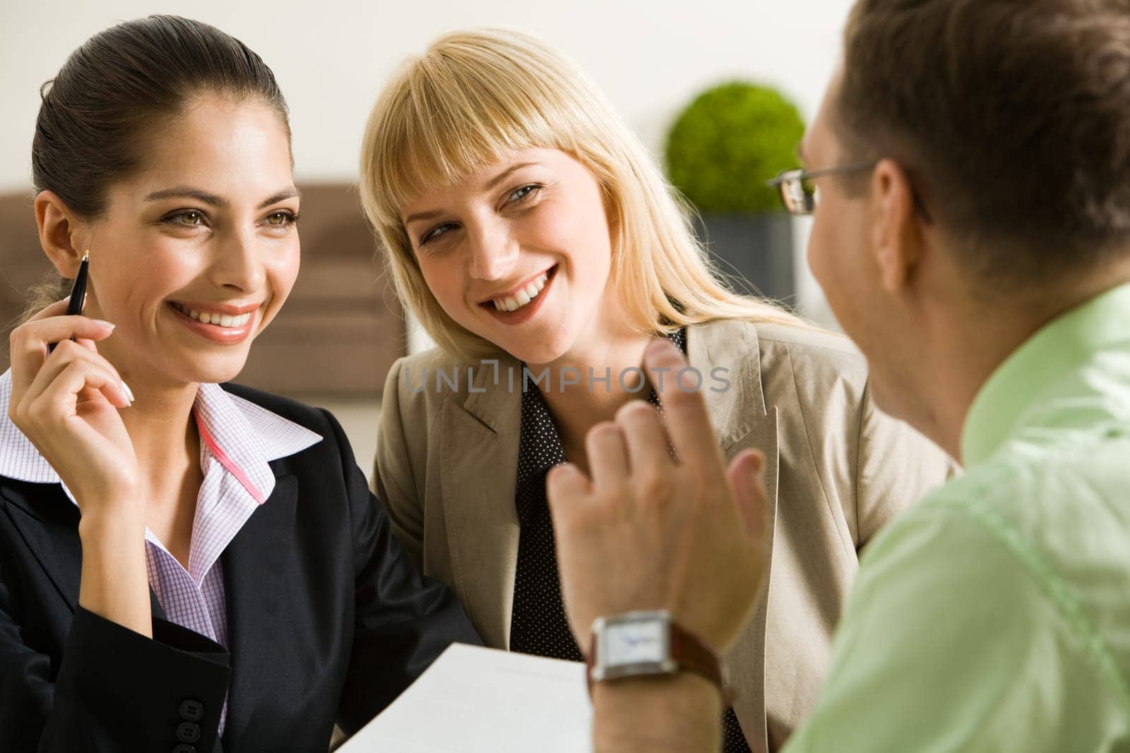 Portrait of three successful business partners discussing new plan at meeting while looking at each other