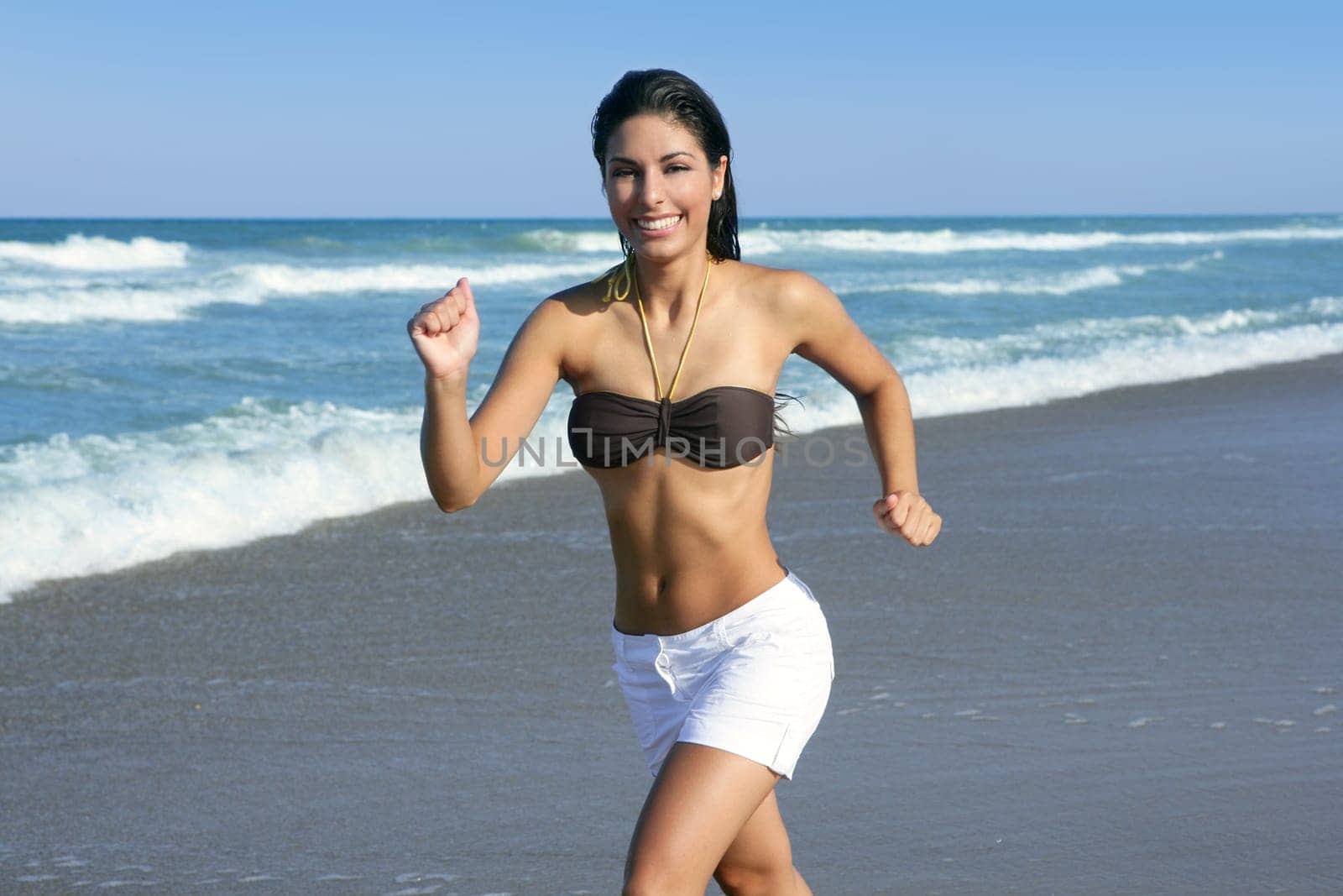 Beautiful summer brunette girl jumping on the blue beach