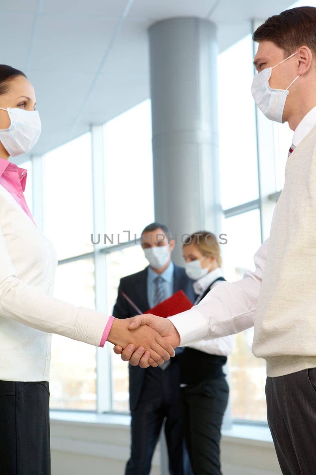 Portrait of successful partners in protective masks handshaking