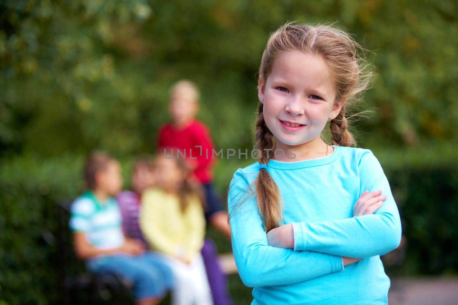 Portrait of happy girl crossing arms and looking at camera with her friends on background