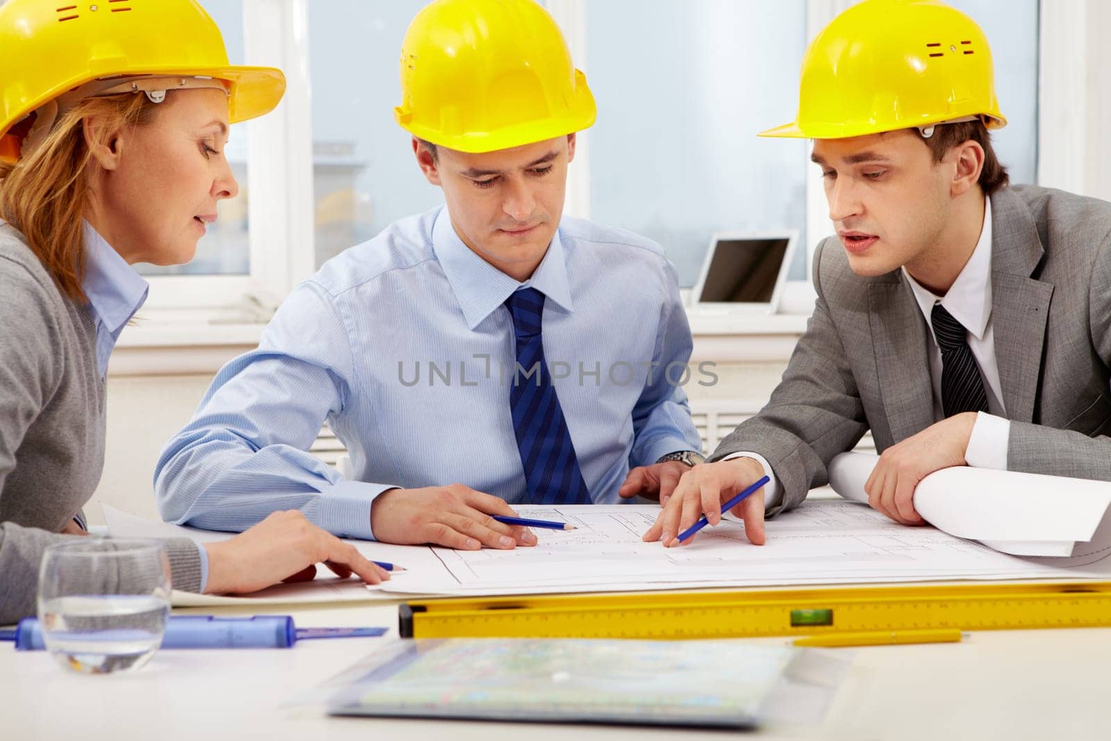Three architects sitting at table and discussing paperwork