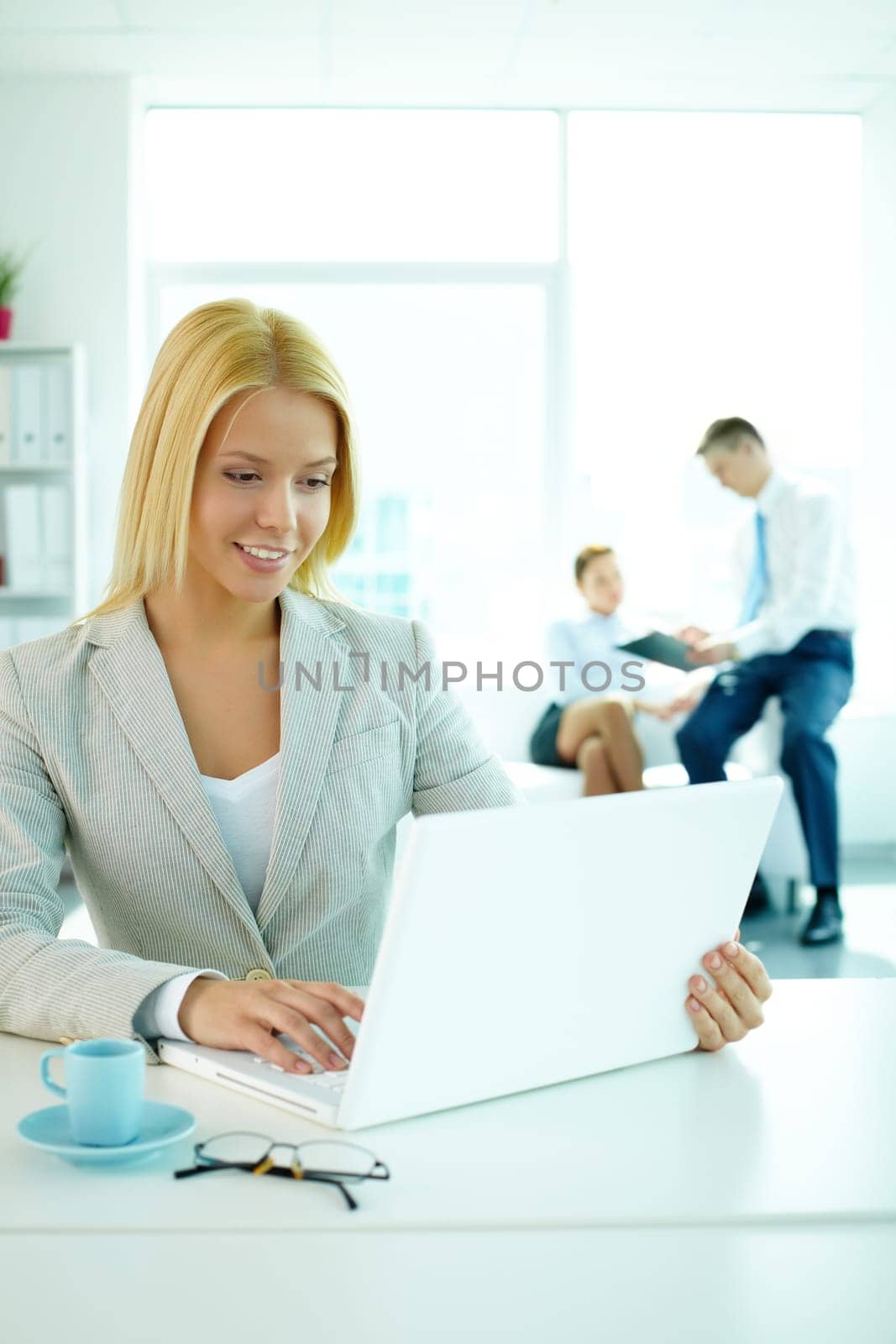 Portrait of pretty secretary looking at laptop screen in working environment
