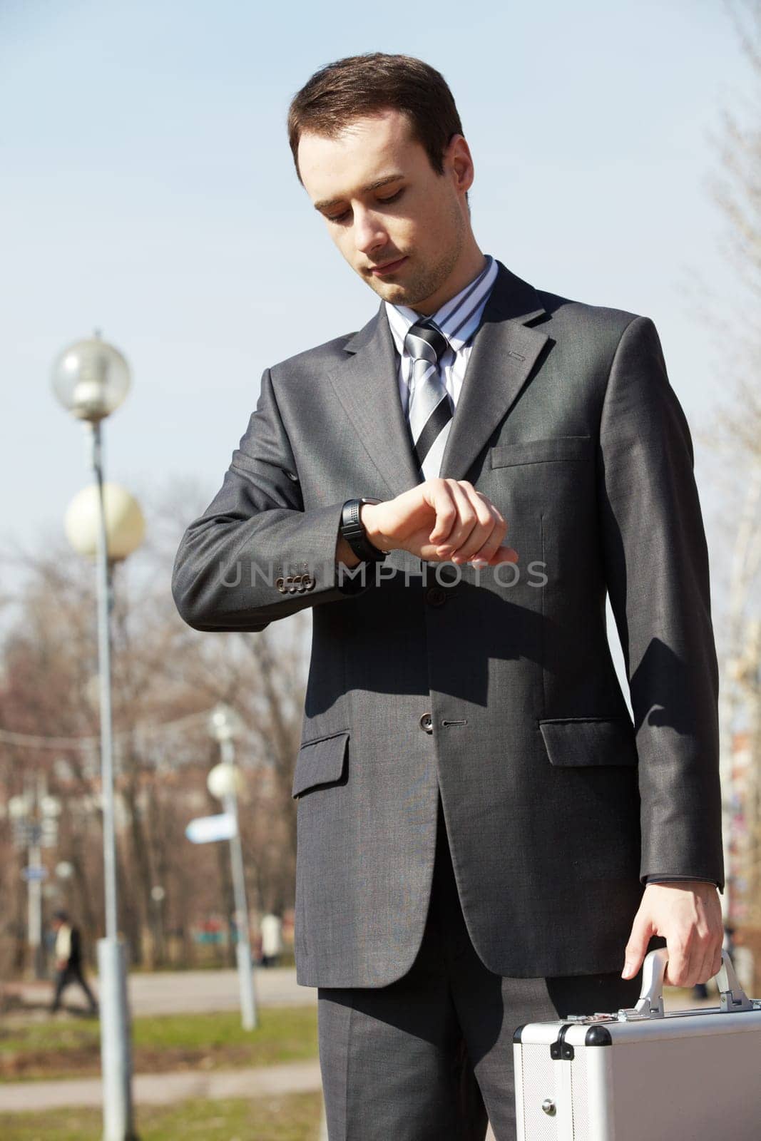 Portrait of elegant businessman looking at his watch outdoors
