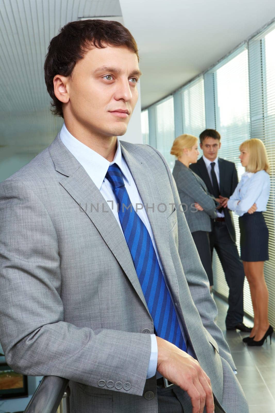Portrait of a young confident businessman with working team on background