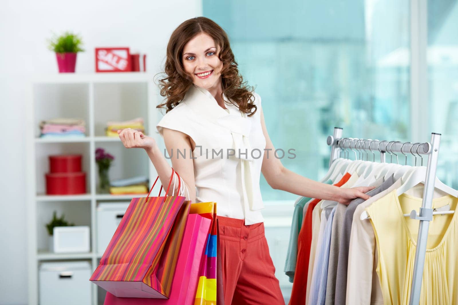 Portrait of pretty woman with colorful bags looking at camera in clothing department