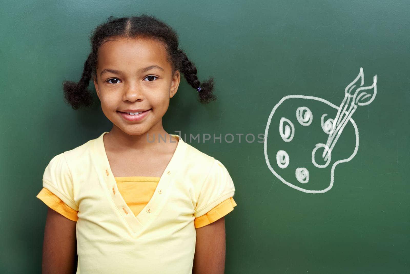 Portrait of cute girl by the blackboard looking at camera