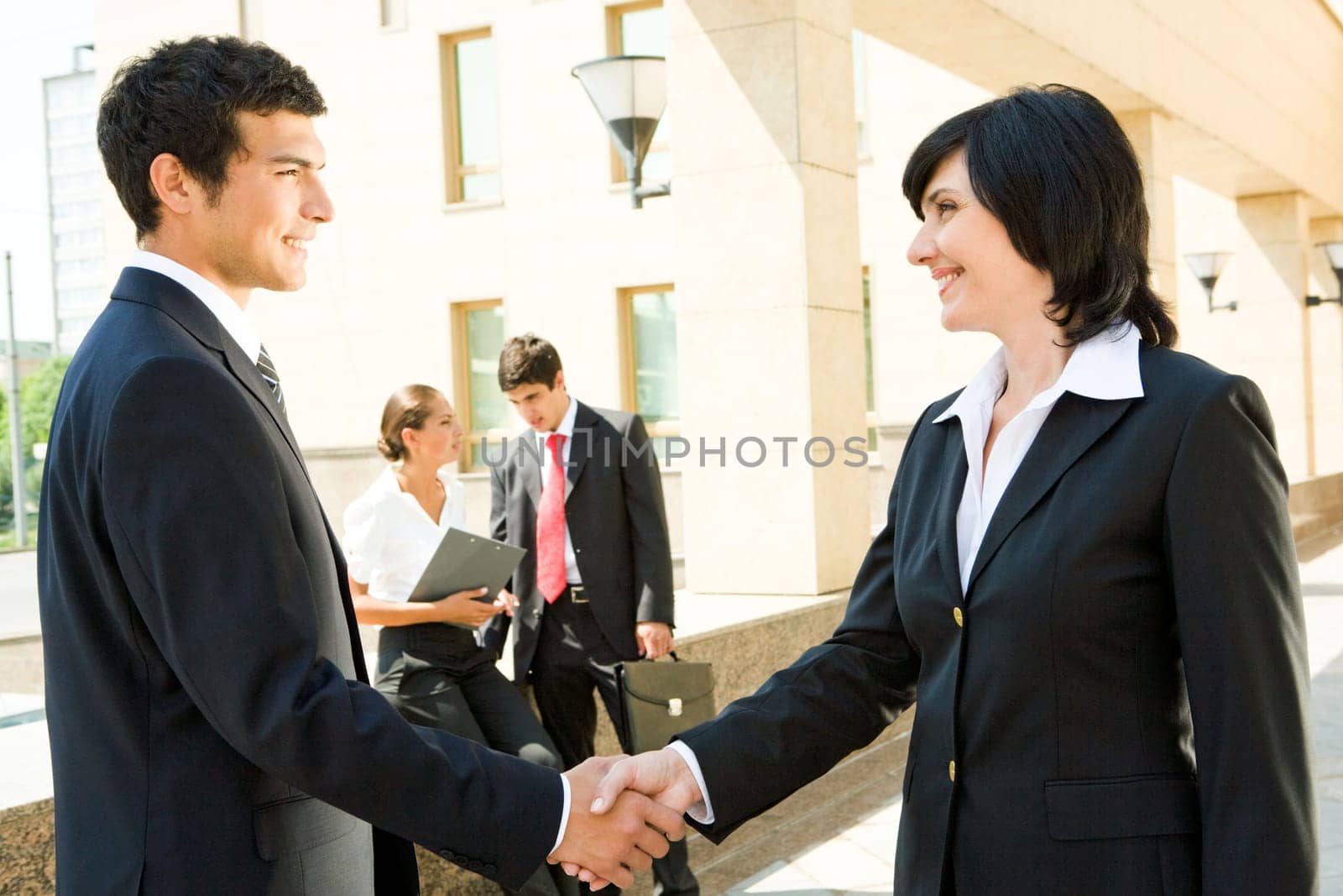 Photo of successful people handshaking with working partners at background