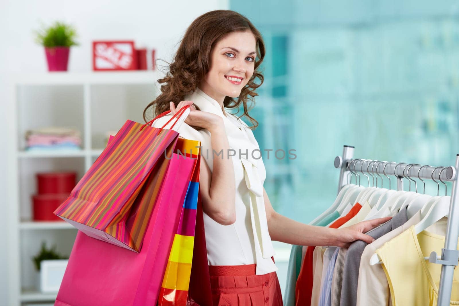 Portrait of pretty woman with colorful bags looking at camera in clothing department