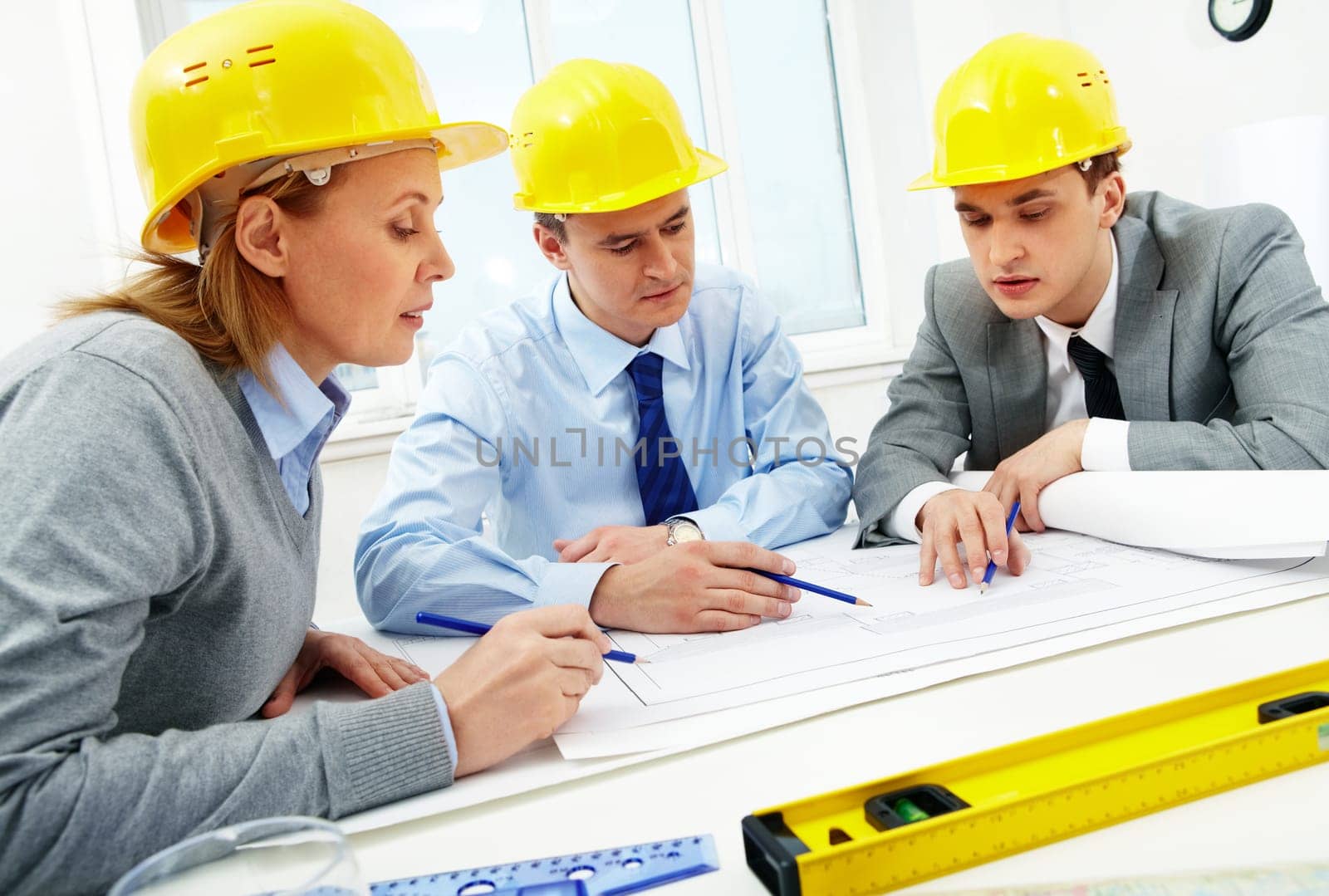 Three architects sitting at table and discussing paperwork