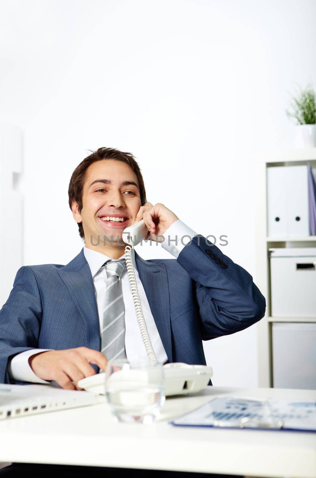 Portrait of happy businessman talking on phone in office