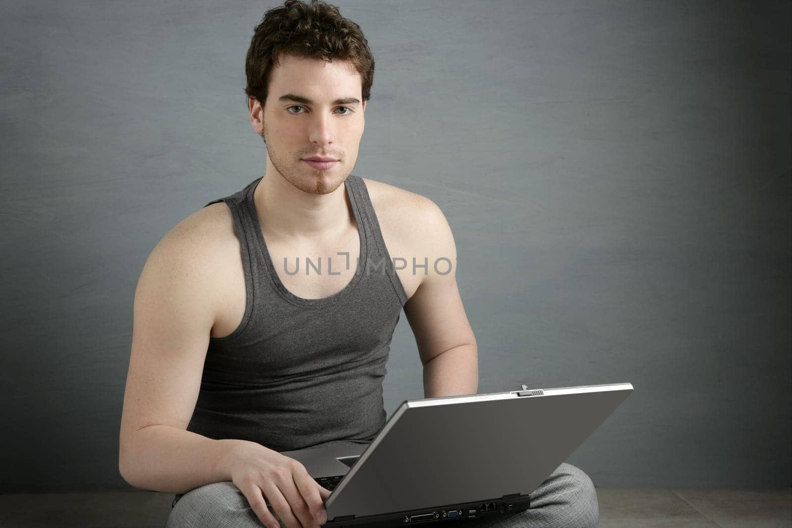 handsome student young man sit working on laptop over gray background