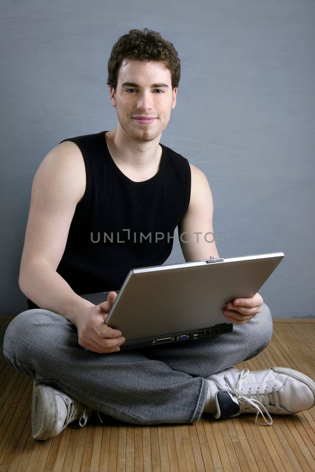handsome student young man sit working on laptop over gray background