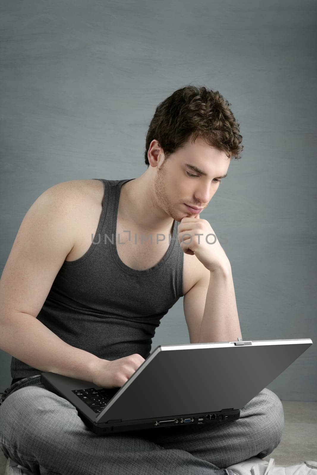handsome student young man sit working on laptop over gray background