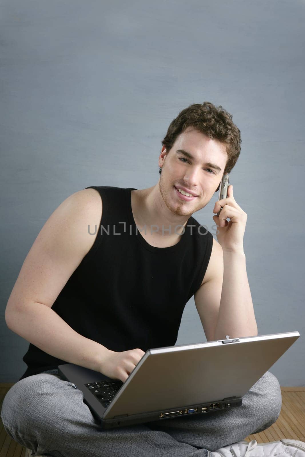 casual student talking mobile phone laptop sit over gray grunge background