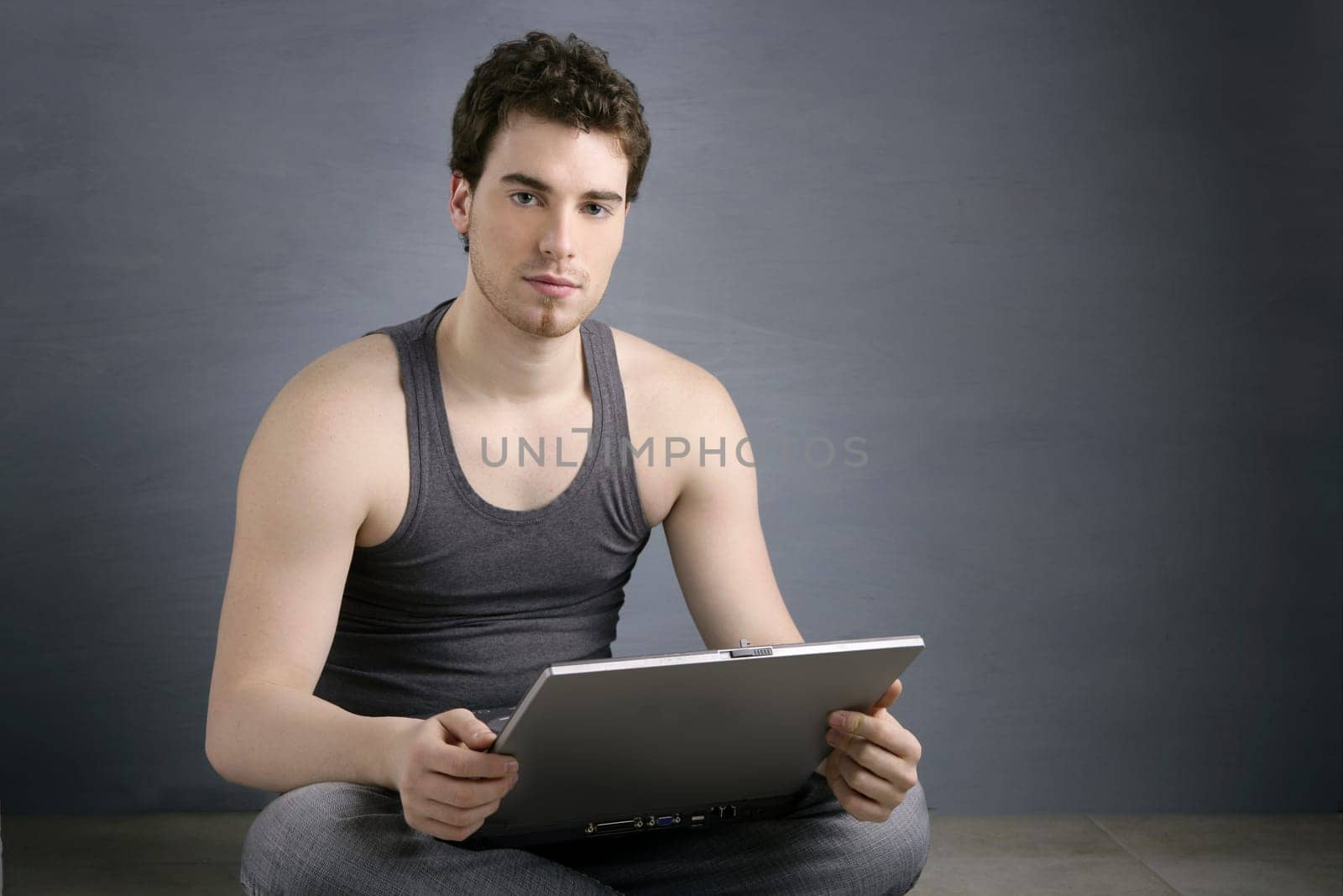 handsome student young man sit working on laptop over gray background