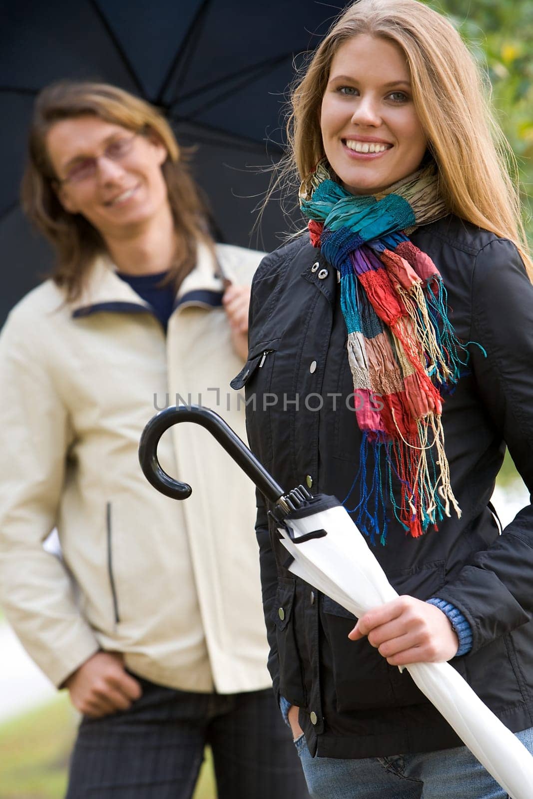 Portrait of happy girl with umbrella on background of her boyfriend
