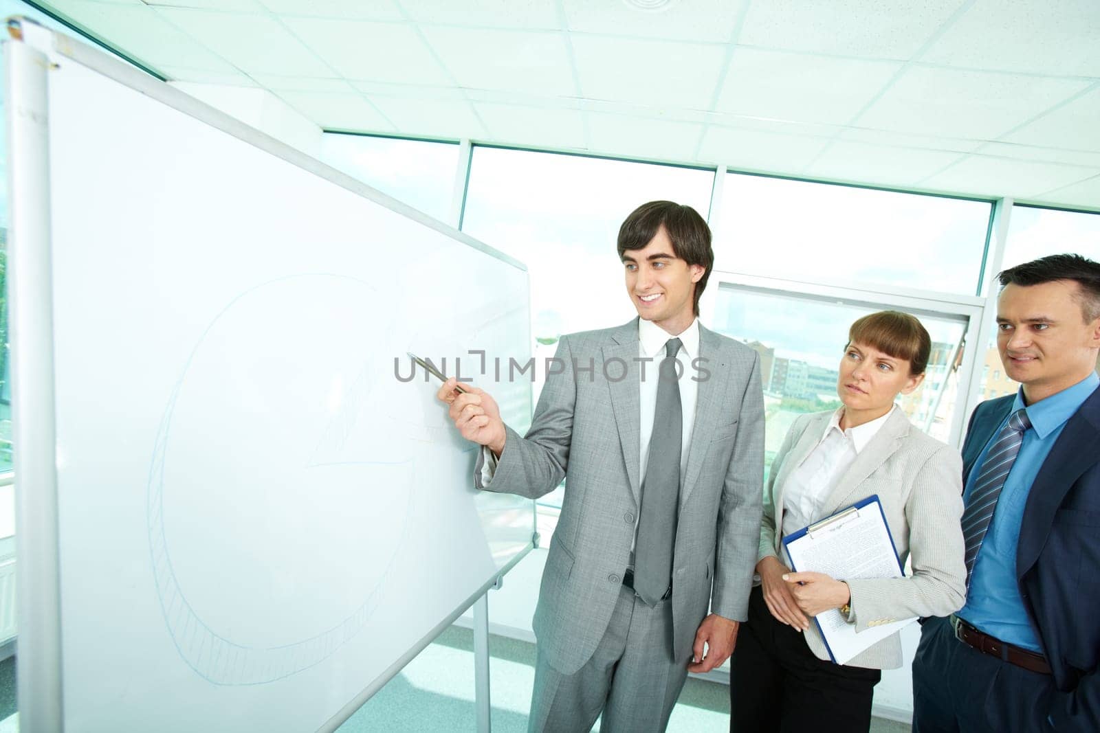 A business man showing something on a whiteboard to his colleagues
