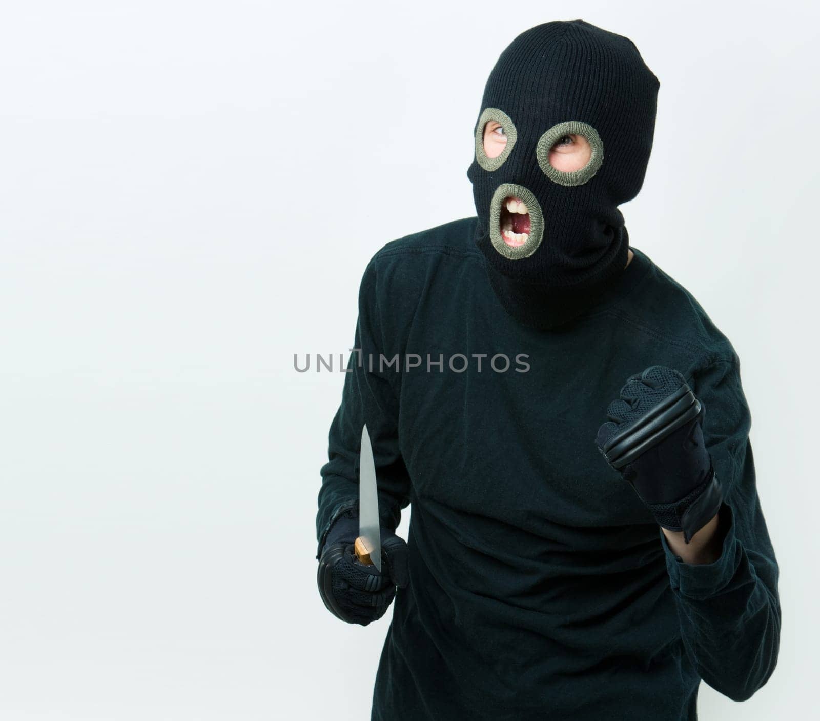 Portrait of felon in balaclava with knife in gloved hand