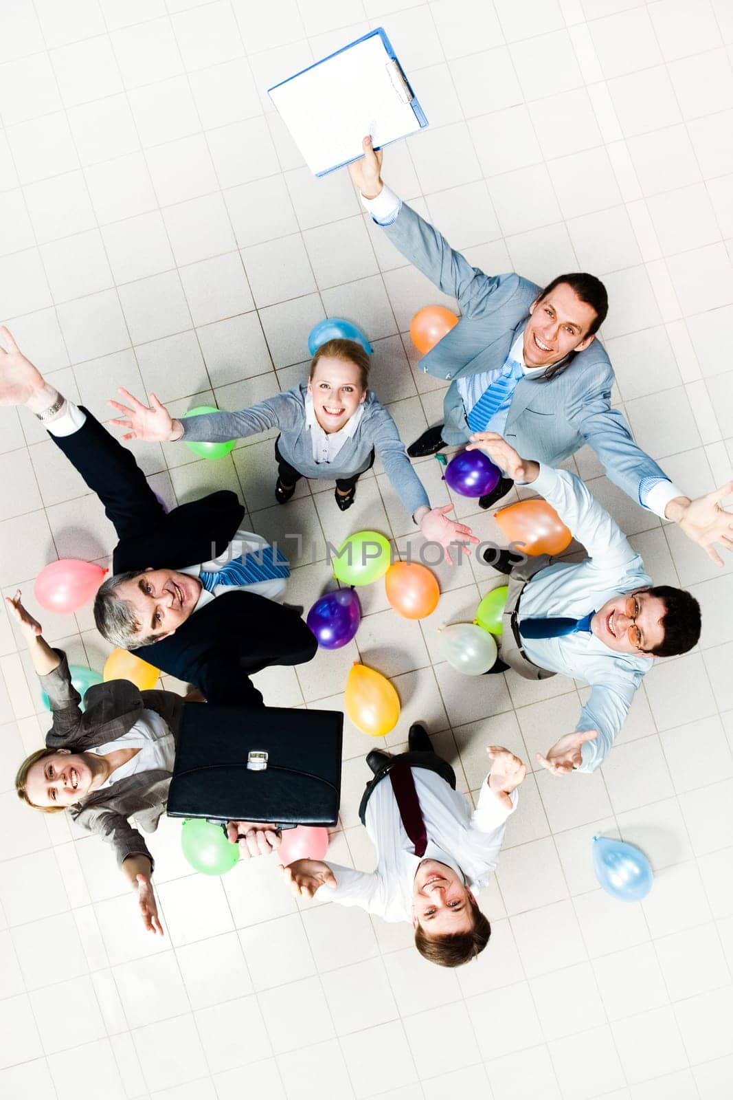 Above view of joyful business people looking at camera with balloons on the floor