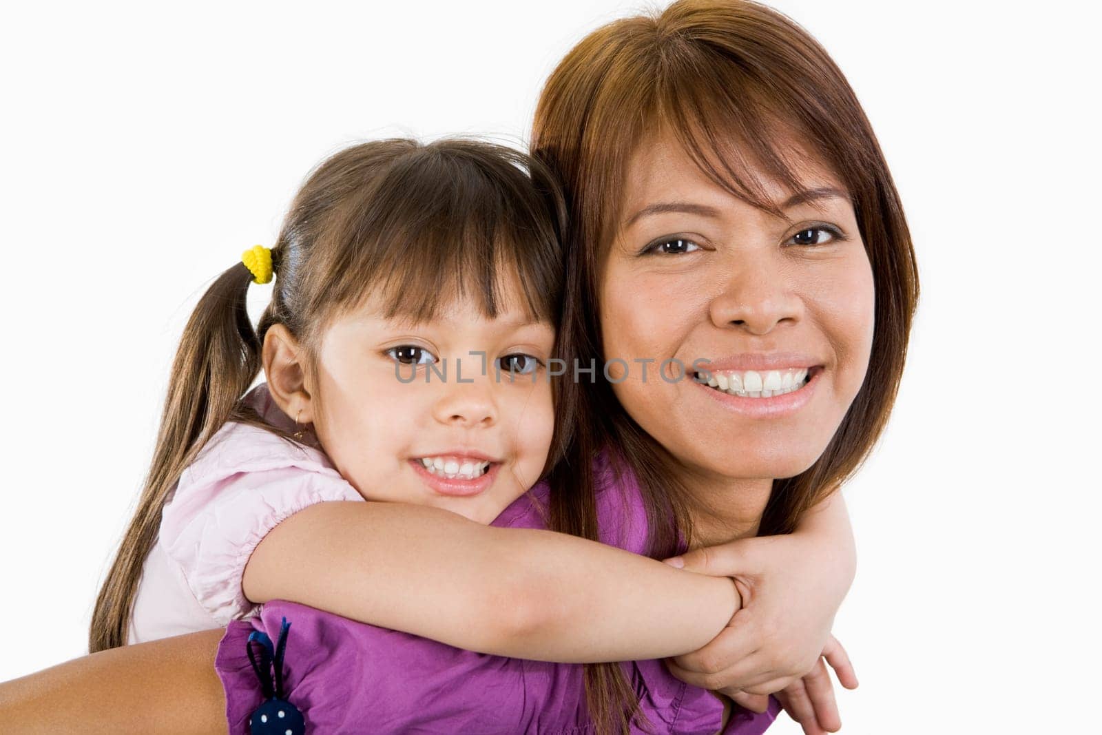 Cute child embracing her beautiful mother and both looking at camera with smiles