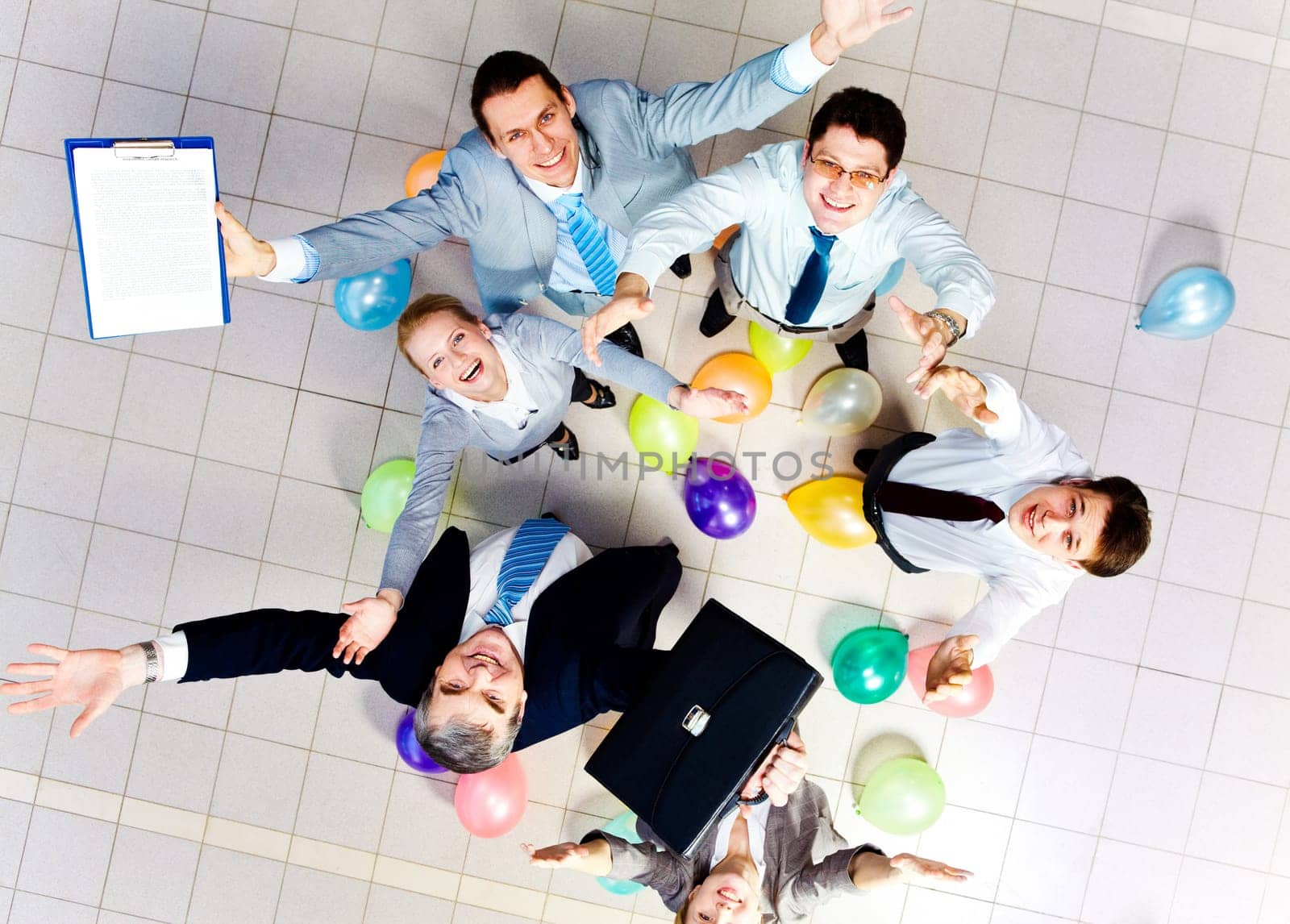 Above view of joyful business people looking at camera with balloons on the floor