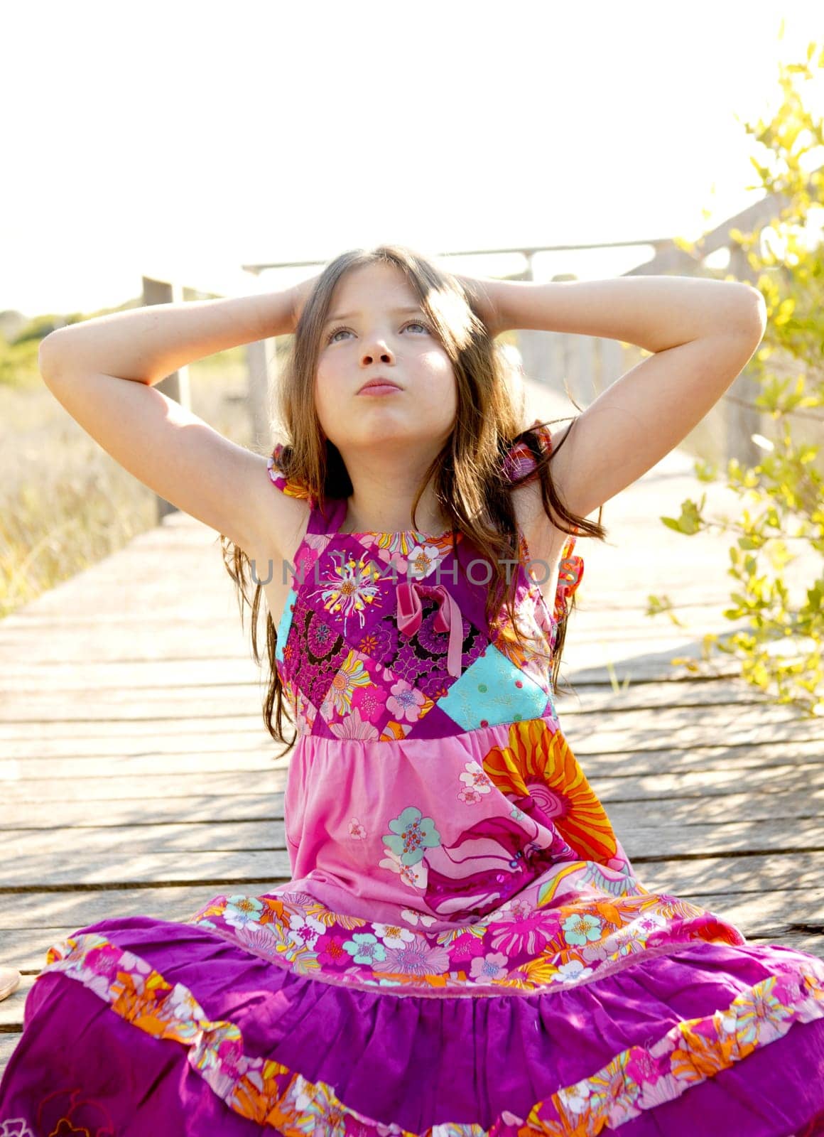 Hippy purple dress teen girl relaxed outdoors, sitting over the park wood