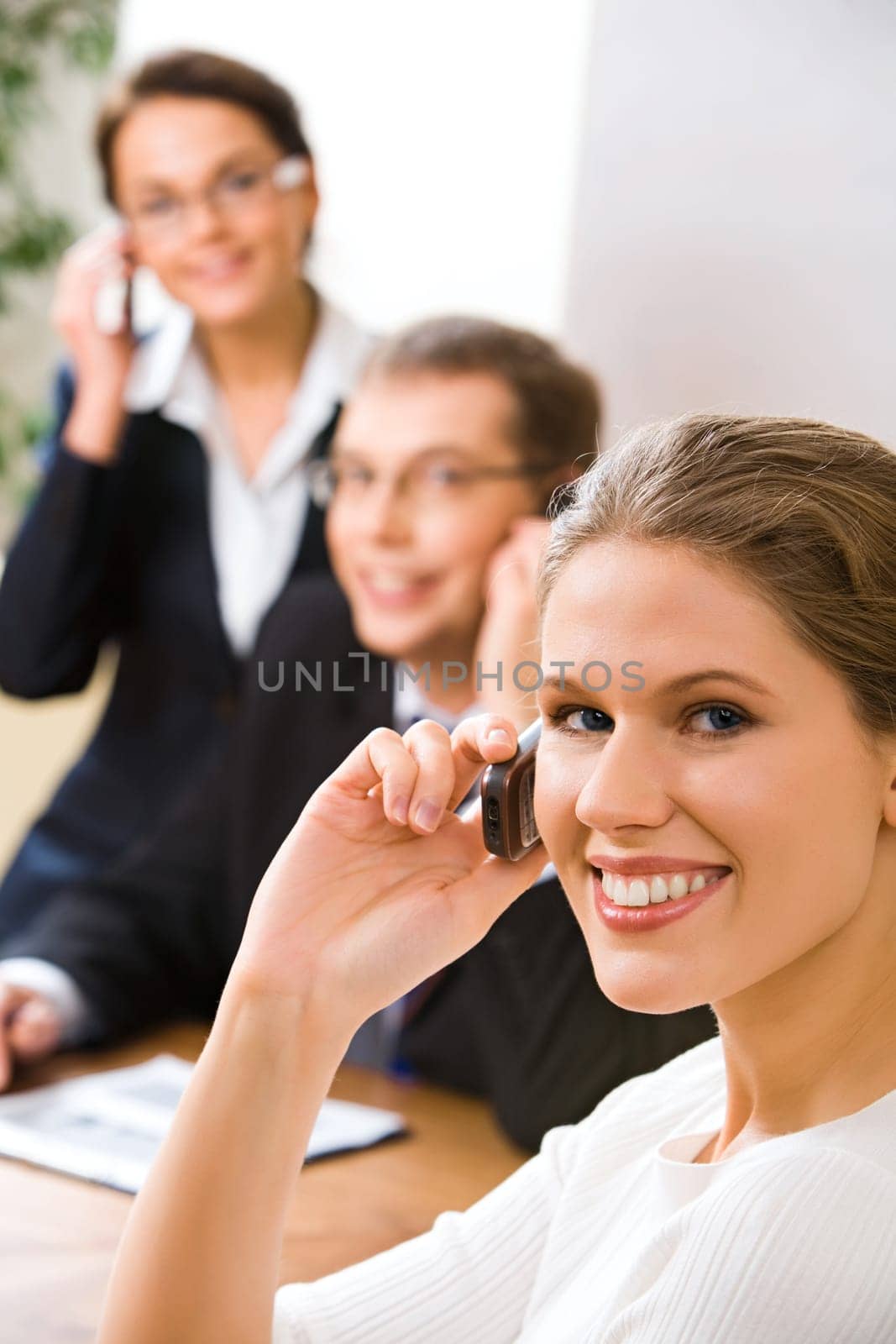 Image of attractive woman calling by mobile on the background of business people