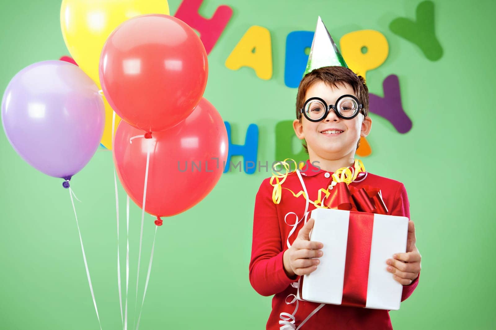 Portrait of happy lad in funny eyeglasses on birthday party with giftbox